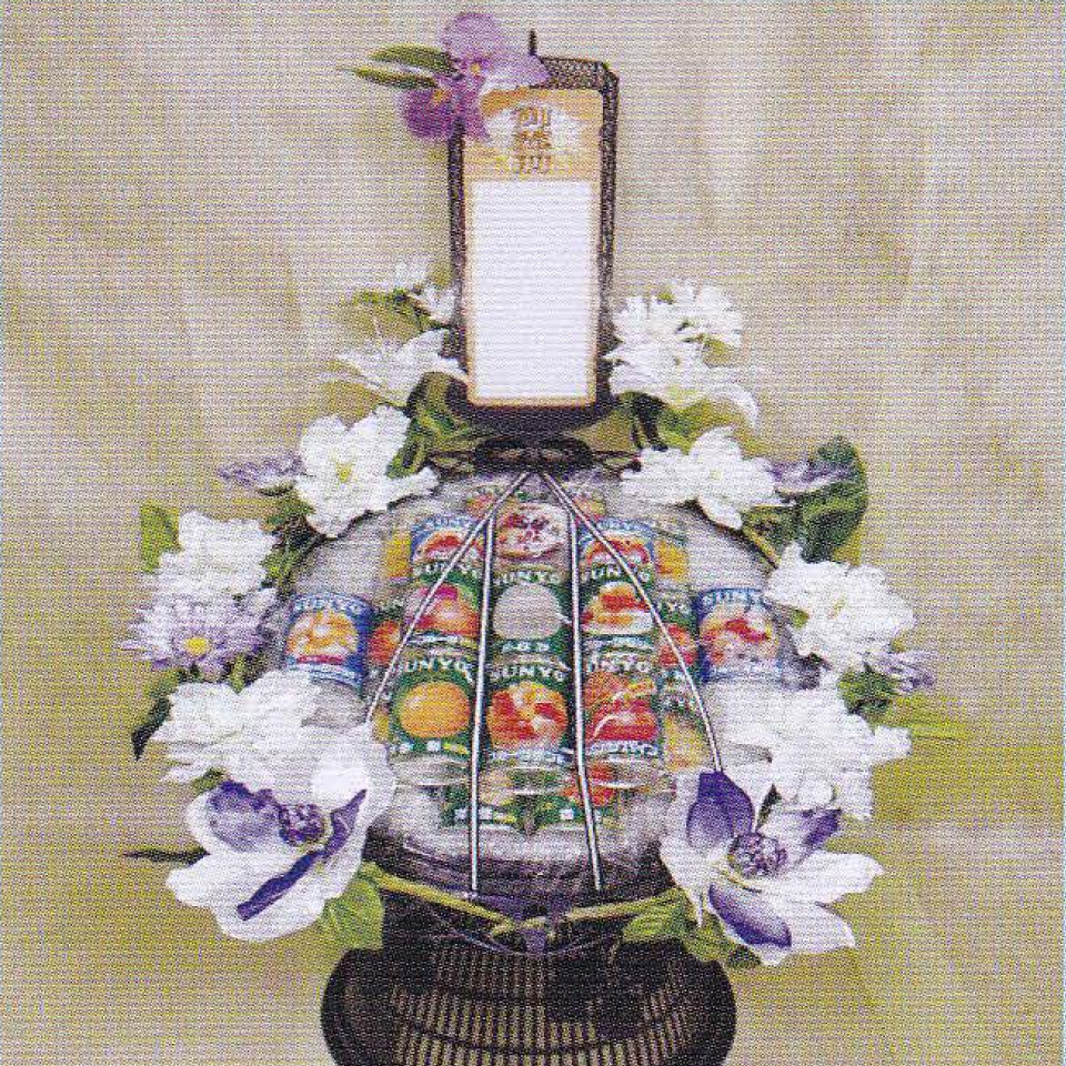 市川市の藤井祭典で提供する周囲に白や紫の花が美しく飾られ、たくさんの缶ジュースで作られている籠