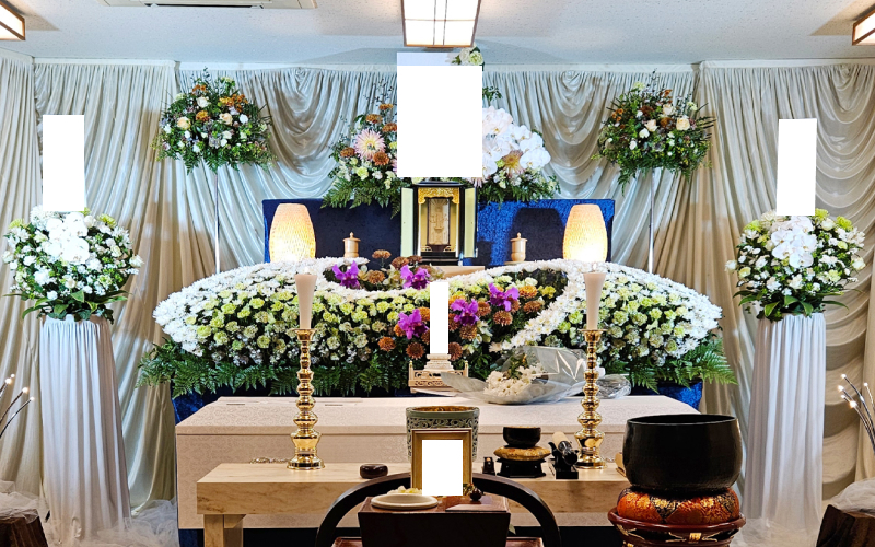 白や黄色の花と祭壇、遺影、仏具の写真